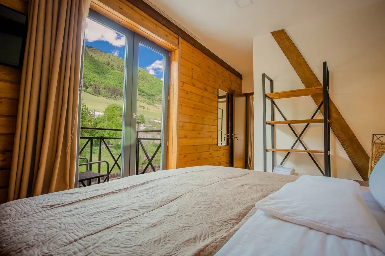 Guest room with balcony opening to a green hillside